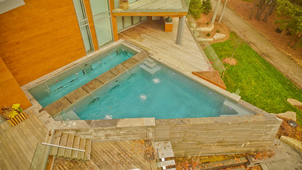 Ejemplo de piscina con fuente infinita contemporánea grande a medida en patio trasero con entablado