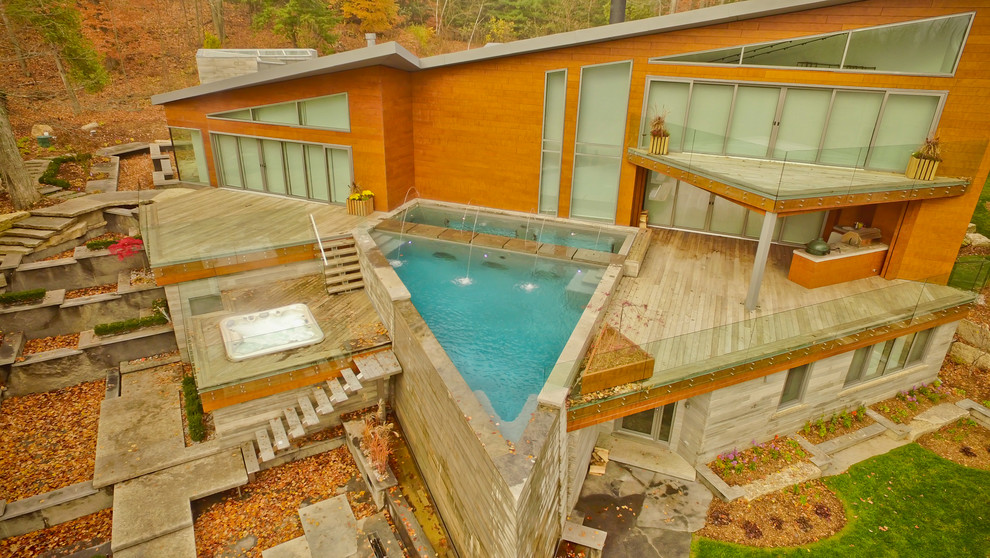 Ispirazione per una grande piscina a sfioro infinito minimal personalizzata dietro casa con fontane e pedane