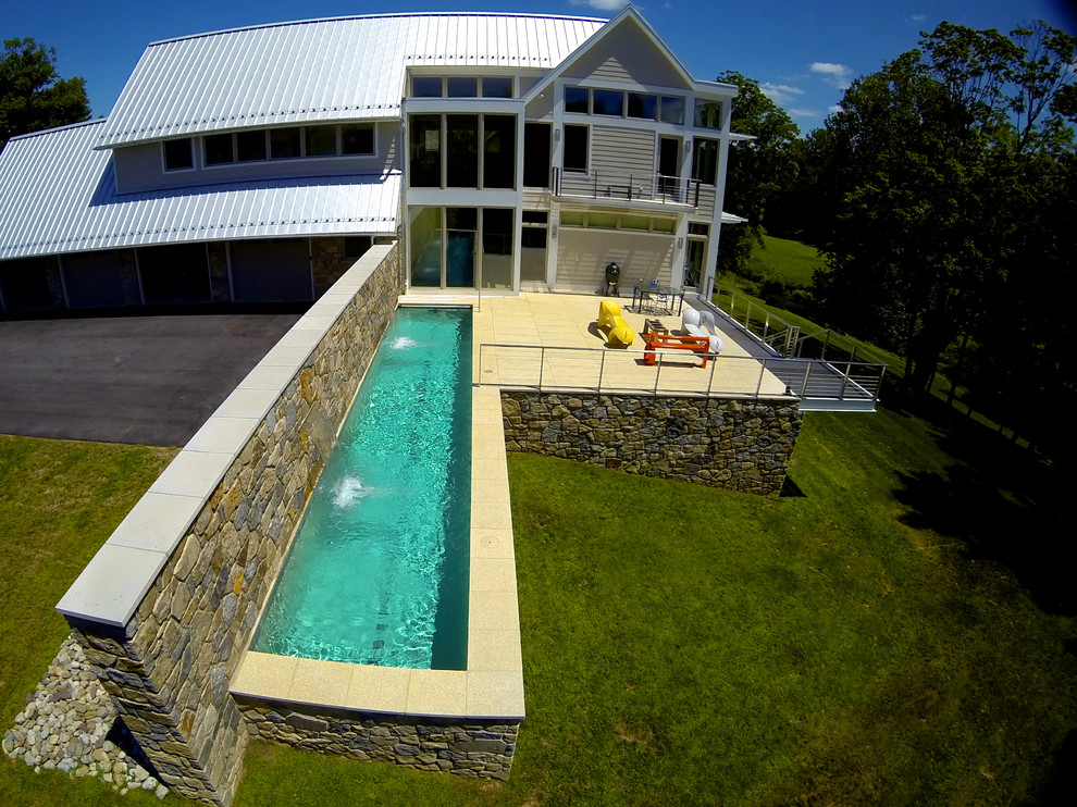 Imagen de piscina con fuente alargada actual de tamaño medio rectangular en patio lateral con adoquines de piedra natural