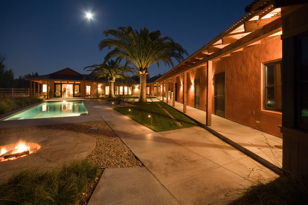 Imagen de piscina actual grande rectangular en patio trasero con adoquines de hormigón