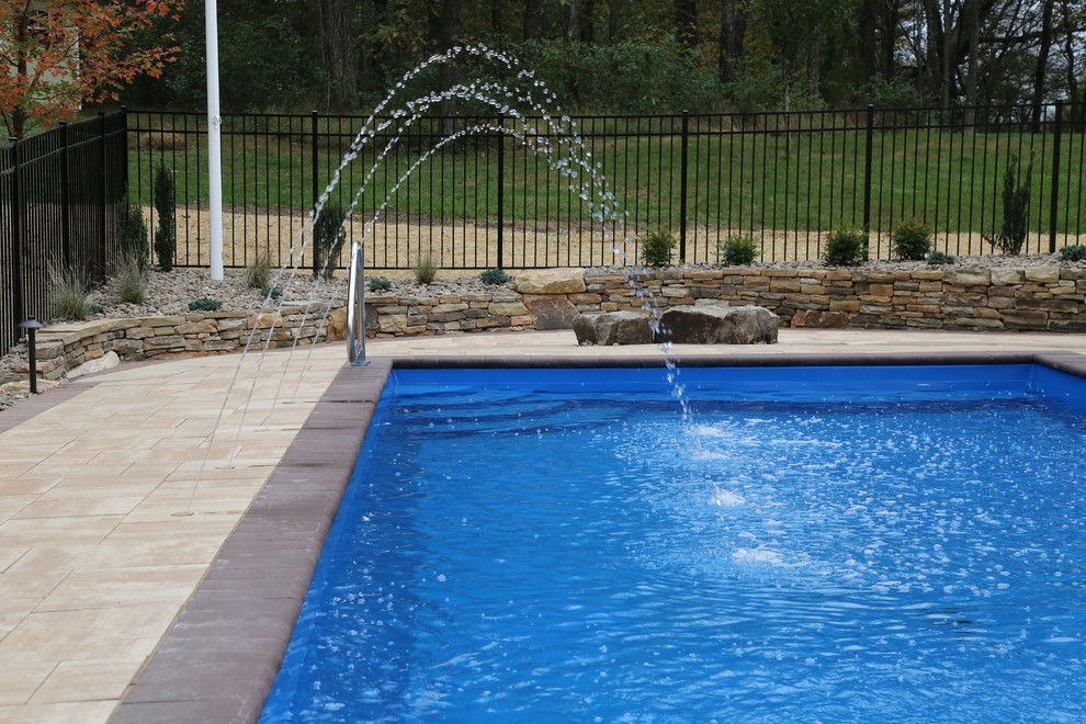 Imagen de piscina con fuente actual de tamaño medio rectangular en patio trasero con adoquines de hormigón