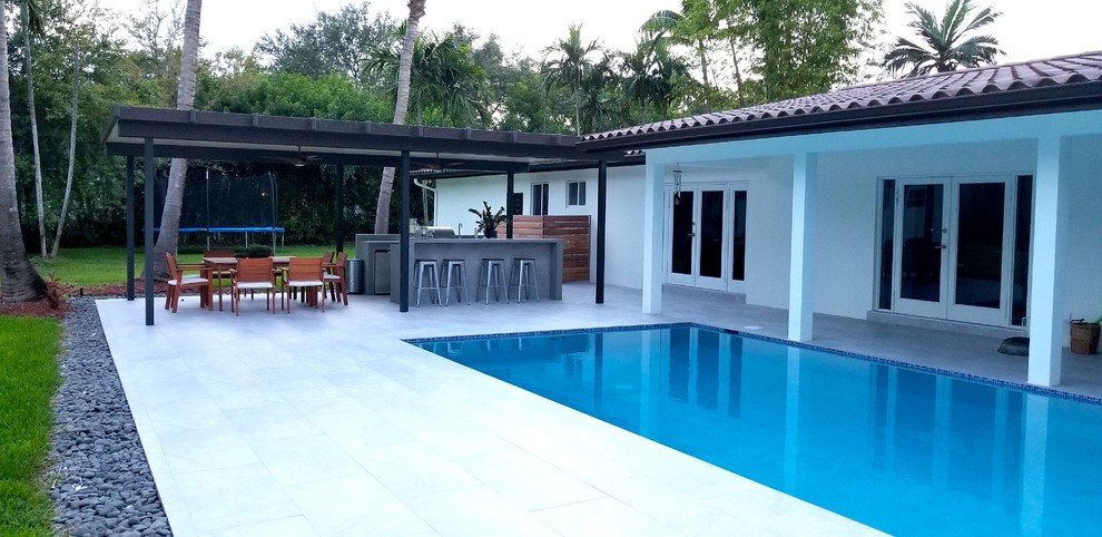 Diseño de piscina alargada contemporánea de tamaño medio rectangular en patio trasero con adoquines de hormigón