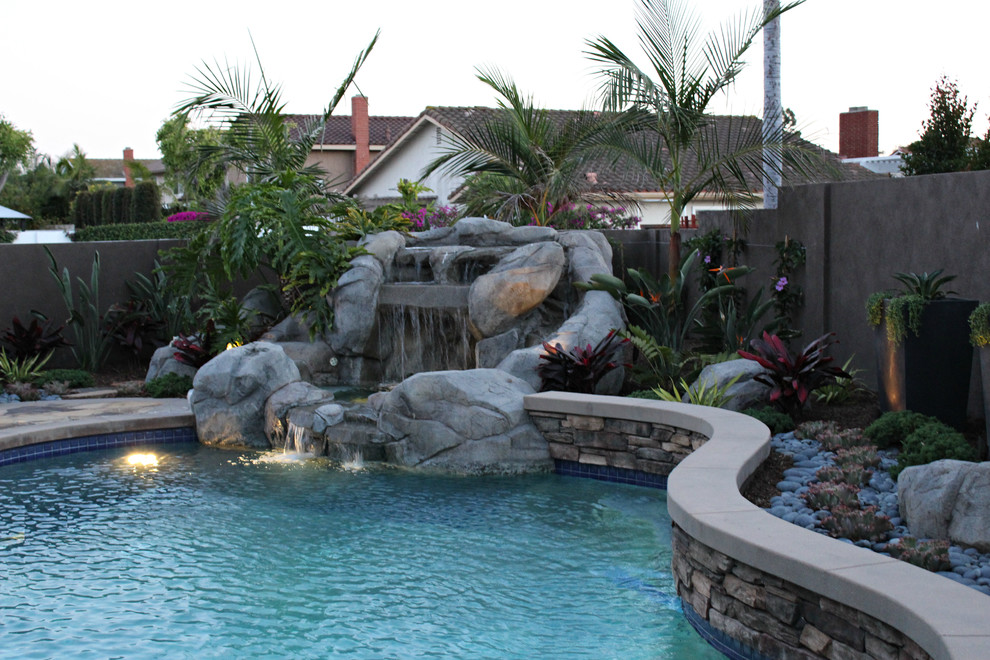 Exemple d'une piscine naturelle et arrière tendance en forme de haricot de taille moyenne avec un point d'eau et des pavés en pierre naturelle.