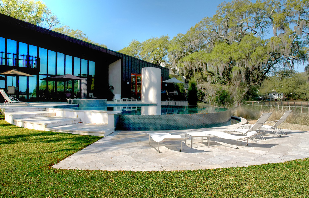 Photo of a contemporary back round infinity swimming pool in Charleston with a water feature and natural stone paving.