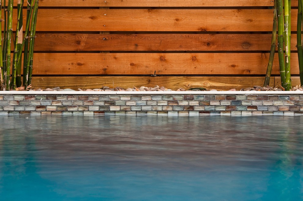 Ejemplo de piscina con fuente alargada actual de tamaño medio rectangular con adoquines de hormigón