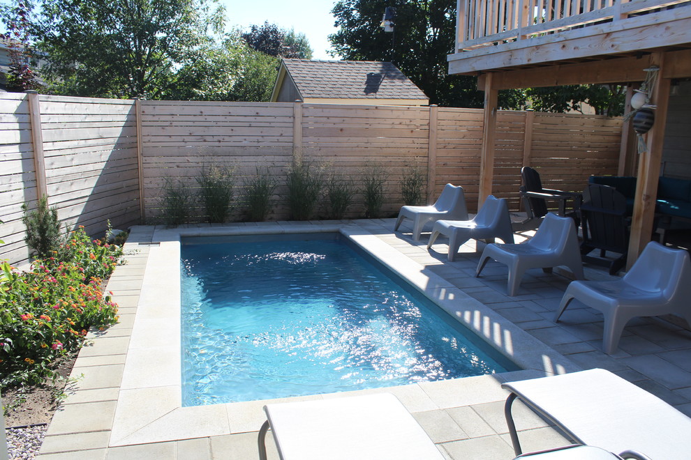 Diseño de piscina alargada actual grande rectangular en patio trasero con adoquines de ladrillo