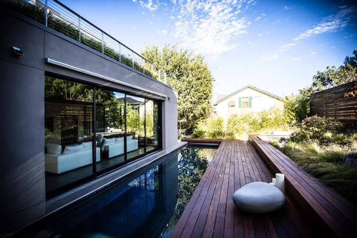 Foto de piscina con fuente alargada actual de tamaño medio rectangular en patio trasero con entablado