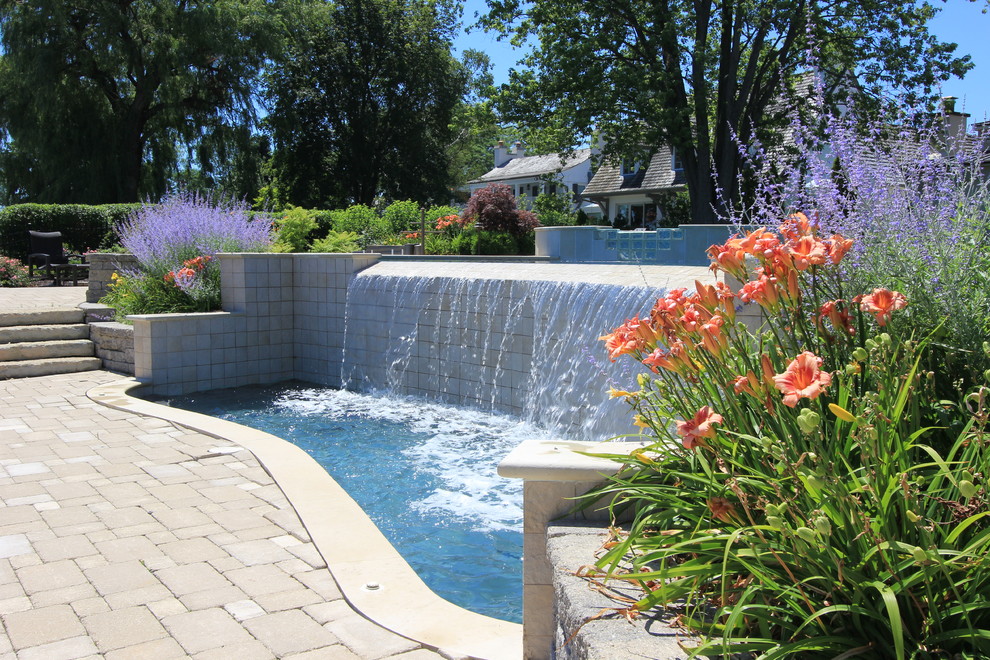 Immagine di una piscina design personalizzata di medie dimensioni e dietro casa con una vasca idromassaggio e pavimentazioni in cemento