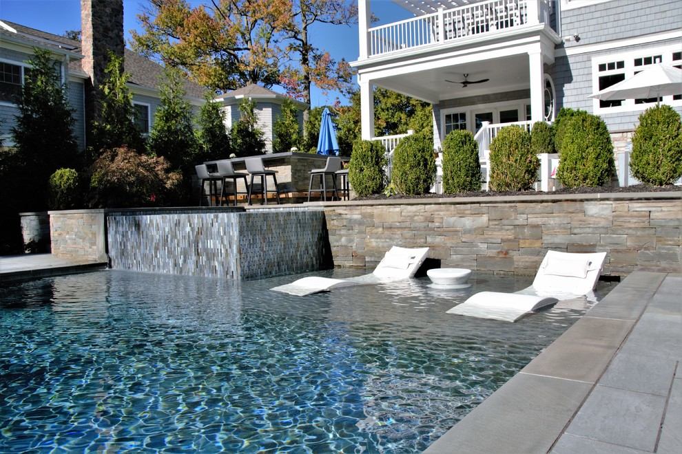 Immagine di una grande piscina monocorsia minimal rettangolare dietro casa con una vasca idromassaggio e pavimentazioni in pietra naturale