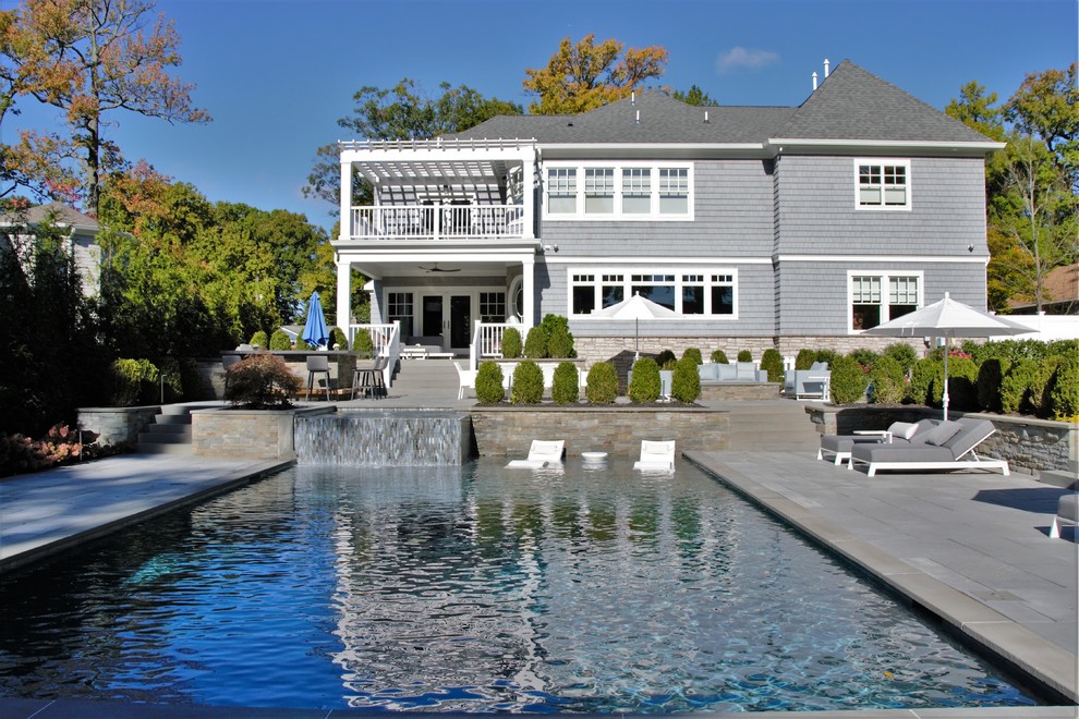 На фото: большой спортивный, прямоугольный бассейн на заднем дворе в современном стиле с джакузи и покрытием из каменной брусчатки с