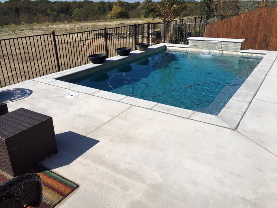 Ejemplo de piscina con fuente alargada contemporánea pequeña rectangular en patio trasero con losas de hormigón