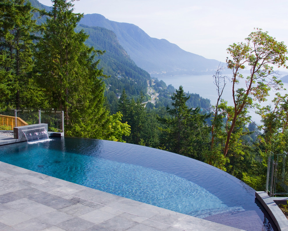Esempio di una piscina a sfioro infinito design personalizzata dietro casa con fontane