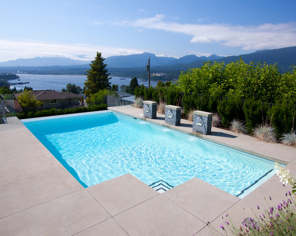 Ejemplo de piscina infinita contemporánea a medida en patio trasero con losas de hormigón