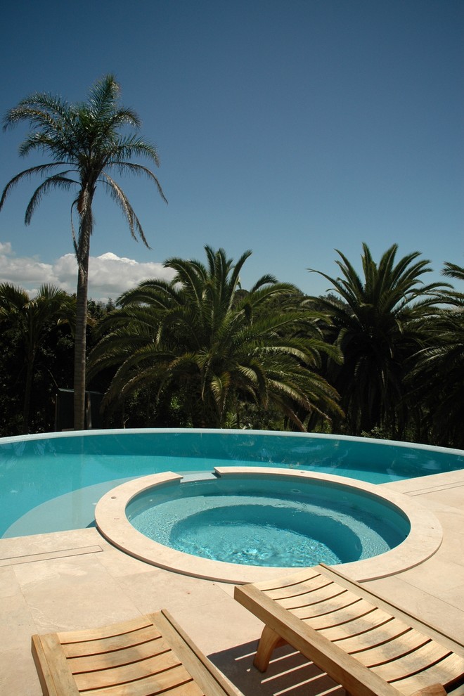 Идея дизайна: бассейн-инфинити произвольной формы в современном стиле с покрытием из бетонных плит