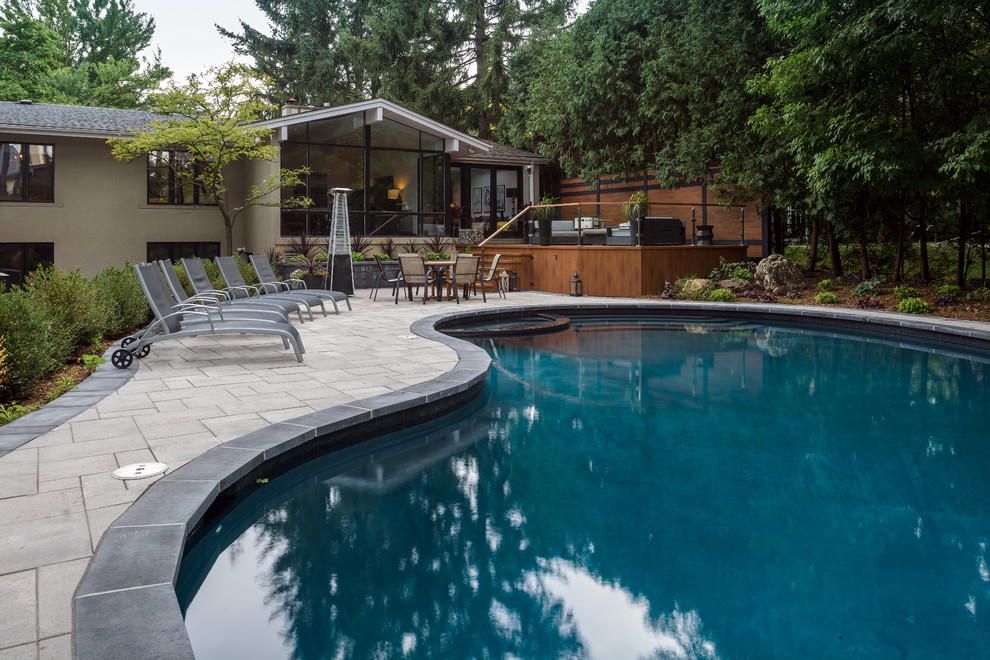 Modelo de piscinas y jacuzzis contemporáneos grandes tipo riñón en patio trasero con adoquines de hormigón