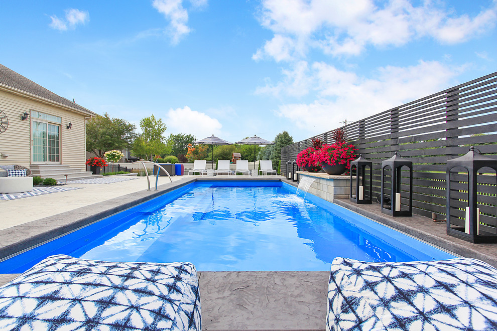 Immagine di una grande piscina monocorsia classica rettangolare dietro casa con una dépendance a bordo piscina e cemento stampato