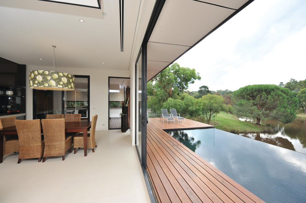 Идея дизайна: прямоугольный бассейн-инфинити на заднем дворе в современном стиле с настилом