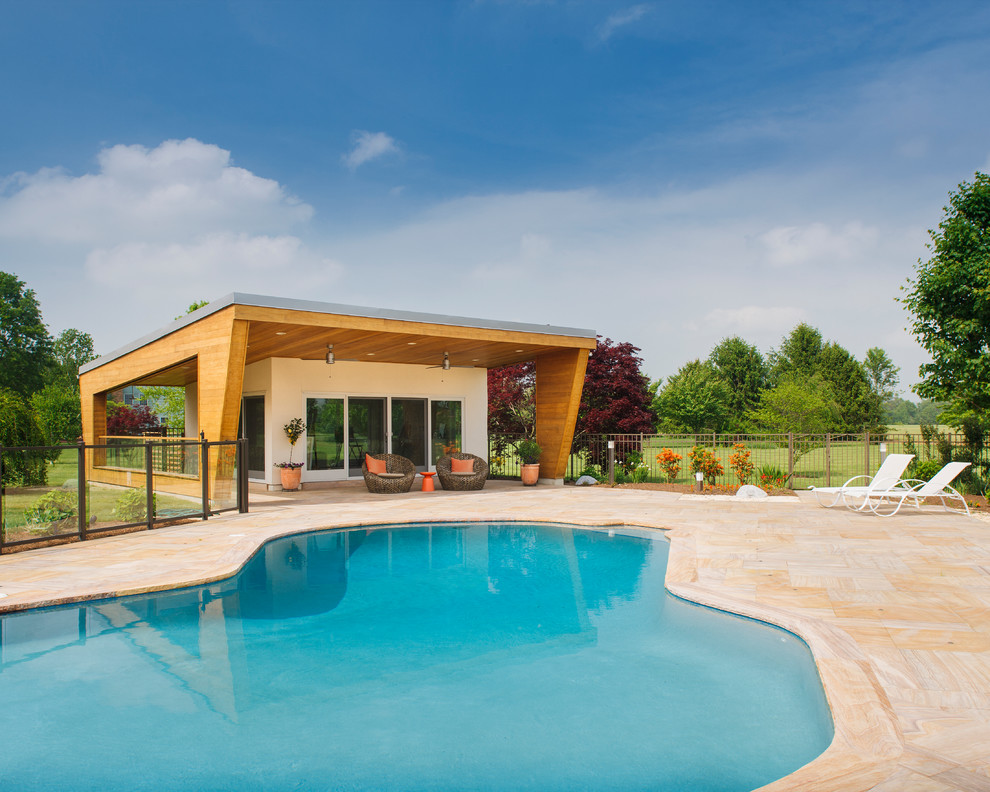 Стильный дизайн: большой бассейн в форме фасоли на заднем дворе в современном стиле с домиком у бассейна и покрытием из каменной брусчатки - последний тренд