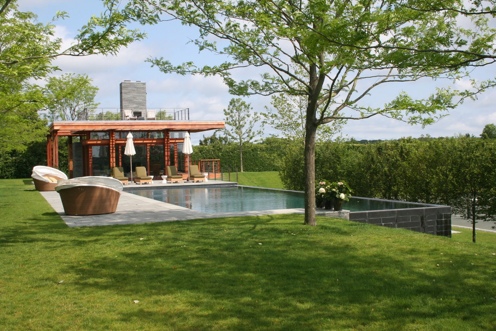 Contemporary infinity swimming pool in Boston with decking and a pool house.