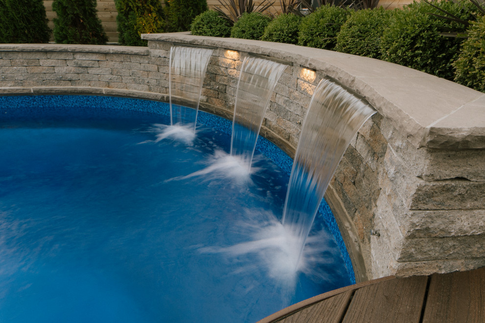 Foto de piscina actual de tamaño medio en patio trasero con adoquines de hormigón