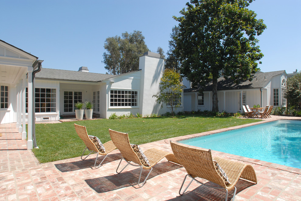 Foto de piscina alargada clásica grande rectangular en patio trasero con adoquines de ladrillo