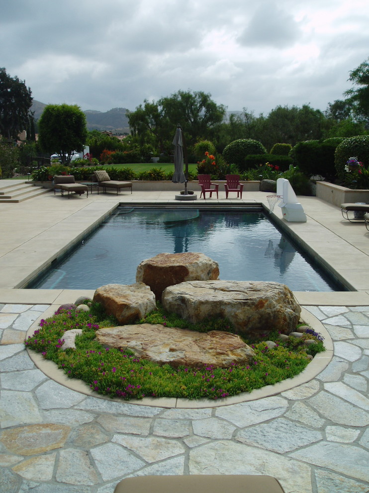 Modelo de piscina contemporánea rectangular en patio trasero con losas de hormigón