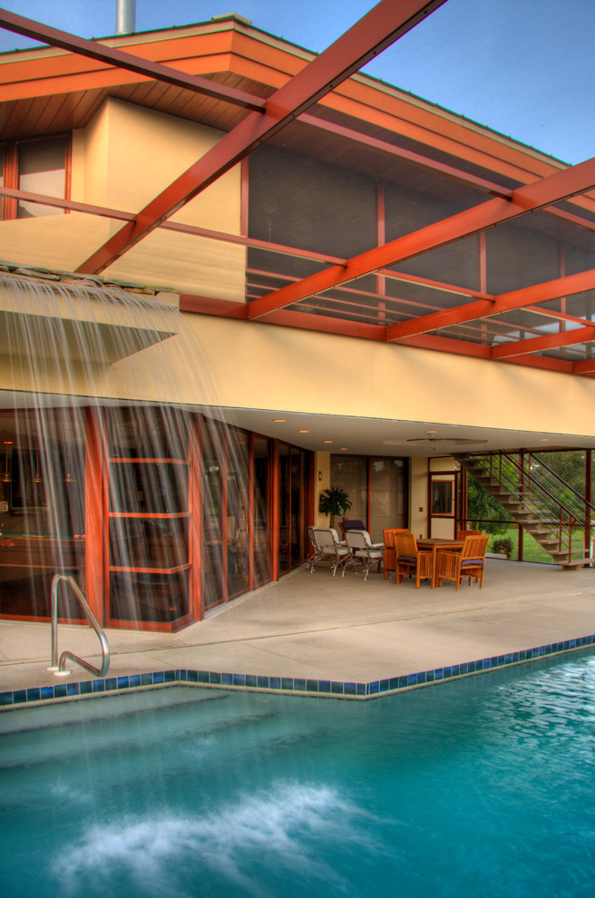 Immagine di una piscina monocorsia contemporanea rettangolare di medie dimensioni e dietro casa con lastre di cemento e fontane