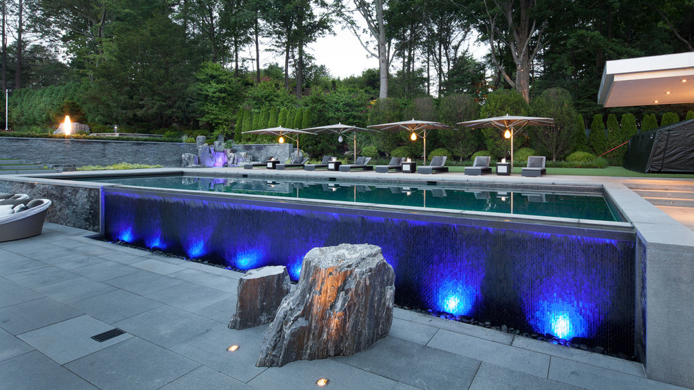 Idee per una grande piscina a sfioro infinito minimal rettangolare dietro casa con fontane e pavimentazioni in cemento