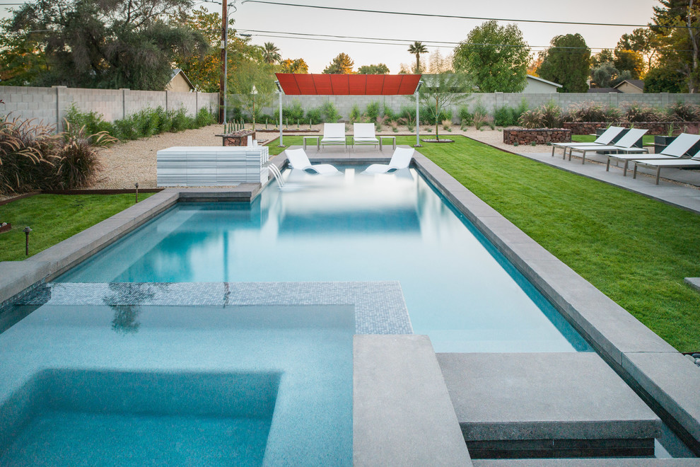 This is an example of a large contemporary back rectangular lengths hot tub in Phoenix with concrete slabs.