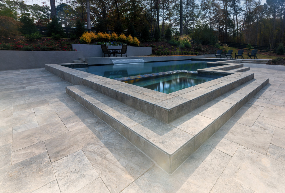Foto på en mellanstor amerikansk pool på baksidan av huset, med en fontän och naturstensplattor