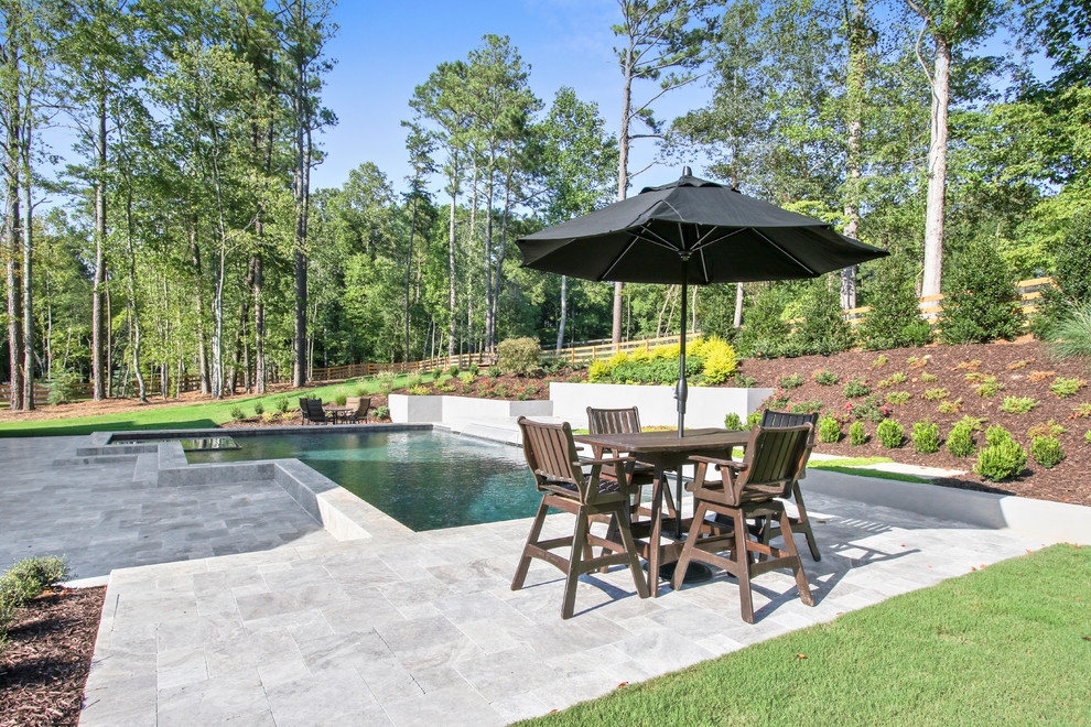 Diseño de piscina con fuente actual de tamaño medio a medida en patio trasero con adoquines de piedra natural