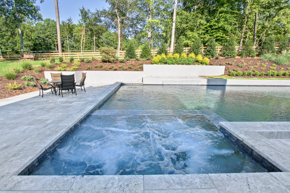 Immagine di una piscina minimalista personalizzata di medie dimensioni e dietro casa con fontane e pavimentazioni in pietra naturale