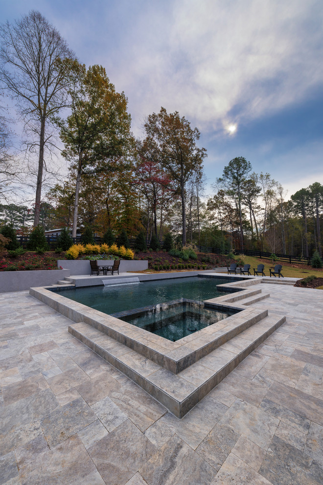 Foto di una piscina moderna di medie dimensioni e dietro casa con fontane e pavimentazioni in pietra naturale