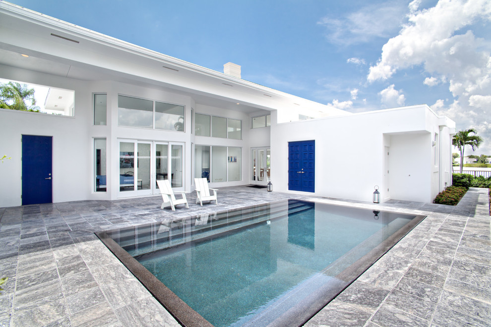 Immagine di una piscina monocorsia minimalista rettangolare di medie dimensioni e dietro casa con piastrelle