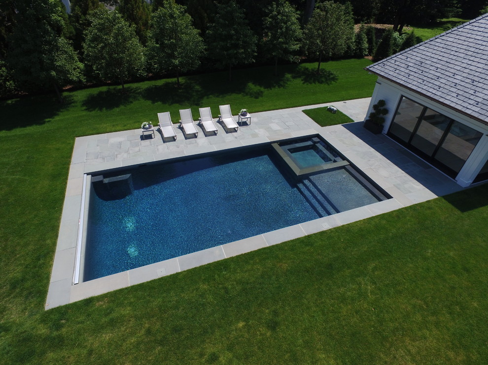 Großes Modernes Poolhaus hinter dem Haus in rechteckiger Form mit Natursteinplatten in New York