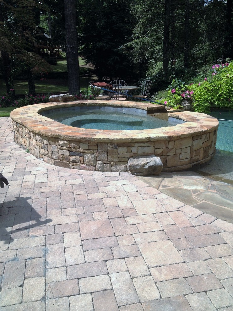 Ejemplo de piscina con fuente natural tradicional grande a medida en patio trasero con adoquines de piedra natural