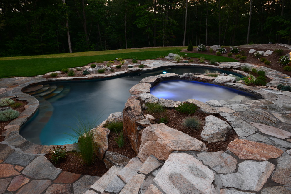 Esempio di una piscina naturale rustica personalizzata di medie dimensioni e dietro casa con una vasca idromassaggio e pavimentazioni in pietra naturale