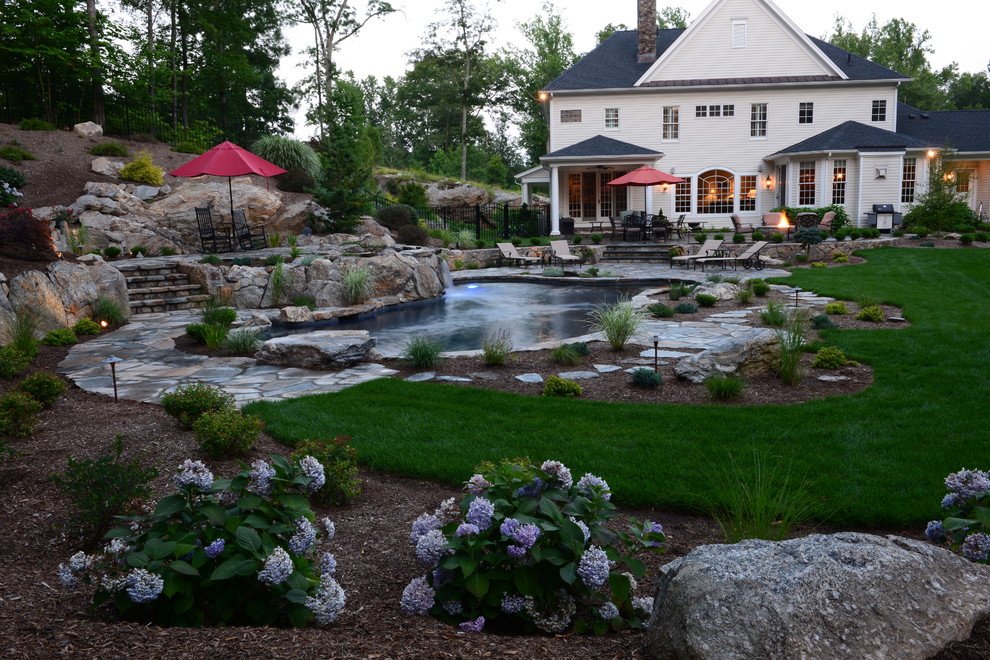 Mid-sized mountain style backyard stone and custom-shaped natural hot tub photo in New York