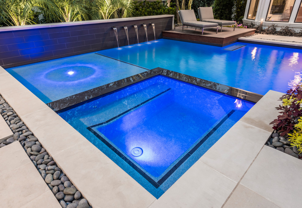 Modelo de piscinas y jacuzzis alargados clásicos renovados de tamaño medio a medida en patio trasero con adoquines de piedra natural