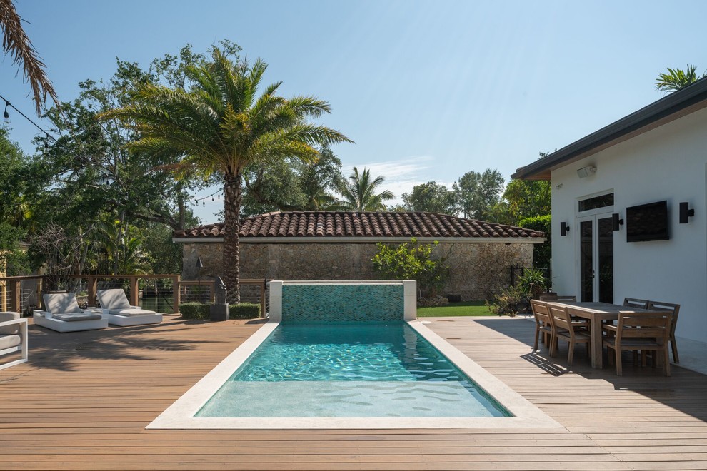 Ejemplo de piscina con fuente mediterránea rectangular con entablado