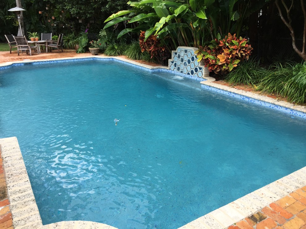 Modelo de piscina con fuente alargada clásica renovada grande rectangular en patio trasero con adoquines de ladrillo