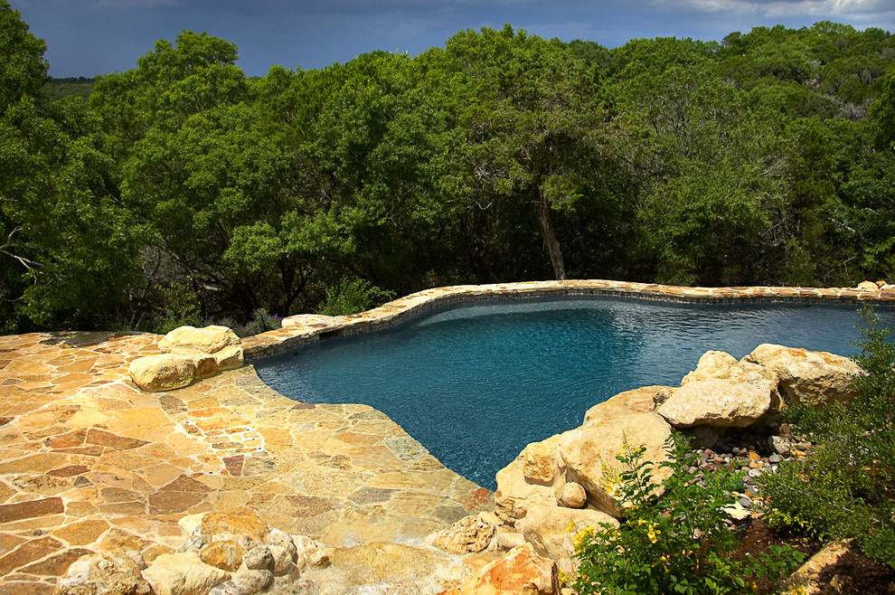 На фото: огромный естественный бассейн произвольной формы на заднем дворе в стиле рустика с фонтаном и покрытием из каменной брусчатки с