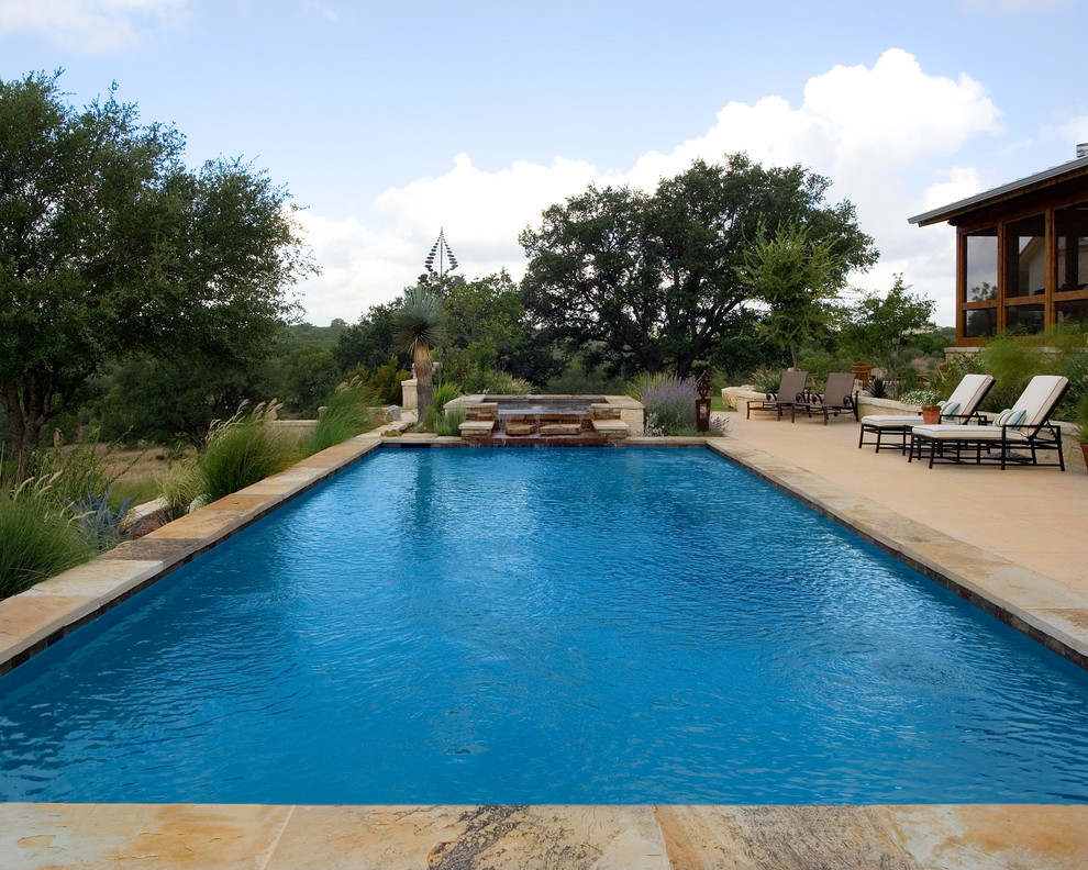 Ejemplo de piscina con fuente alargada actual extra grande rectangular en patio trasero con losas de hormigón