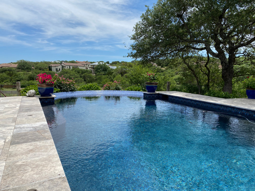 Foto de piscina infinita clásica renovada grande rectangular en patio con adoquines de piedra natural