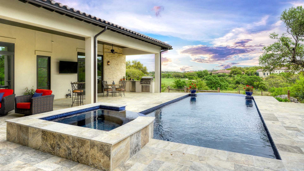 Inspiration for a large classic courtyard rectangular infinity swimming pool in Austin with natural stone paving.