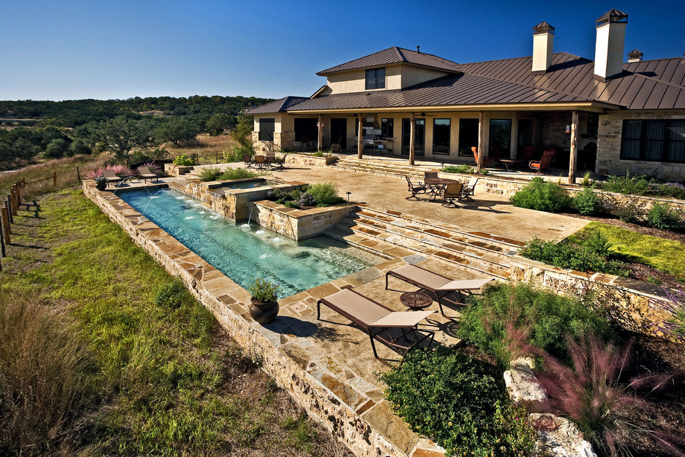 Foto de piscina con fuente alargada rústica grande a medida en patio trasero con losas de hormigón