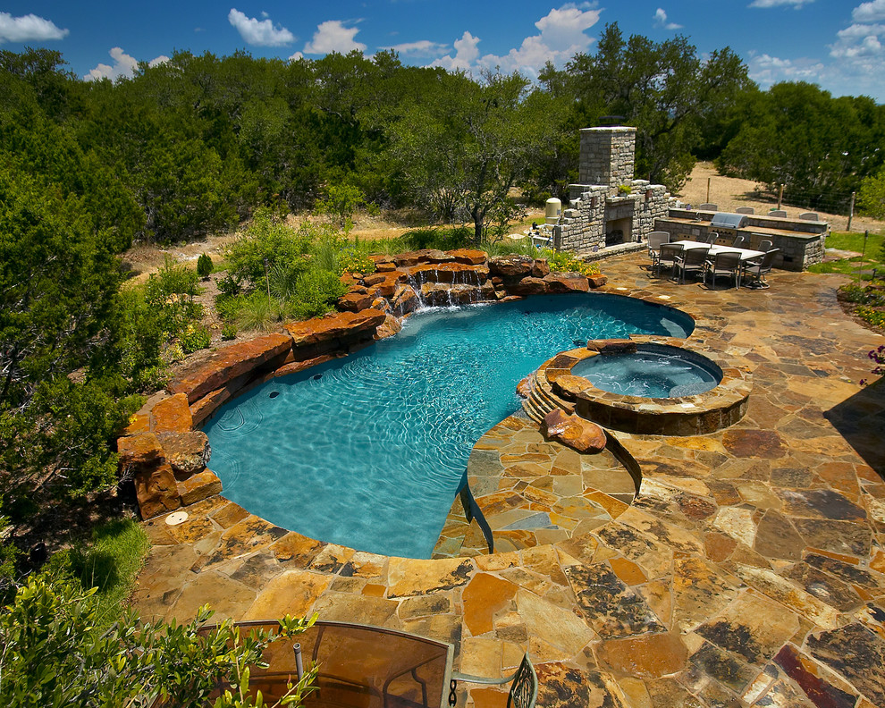 Пример оригинального дизайна: большой естественный бассейн произвольной формы на заднем дворе в стиле рустика с фонтаном и покрытием из каменной брусчатки