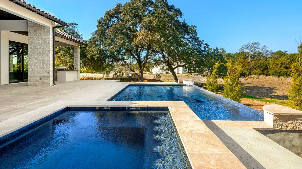 Example of a large classic backyard concrete and rectangular infinity pool design in Austin