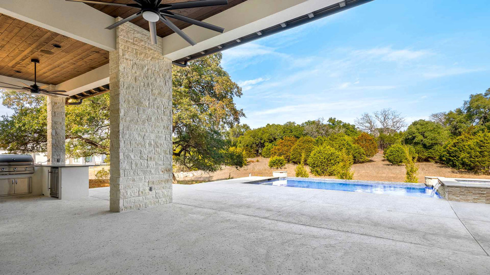 Imagen de piscina infinita clásica grande rectangular en patio trasero con losas de hormigón