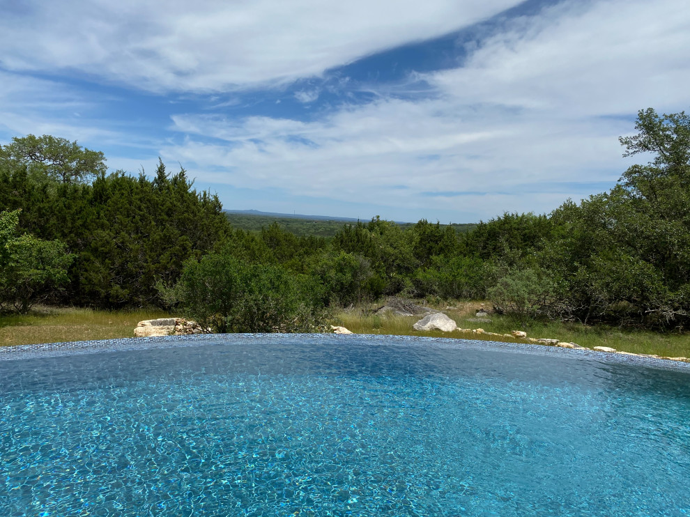 Foto di un'ampia piscina a sfioro infinito minimalista personalizzata dietro casa con pedane